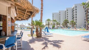 Un área junto a la piscina con sillones de descanso, un bar y piscina.