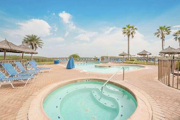 A swimming pool area with lounge chairs and palm trees.