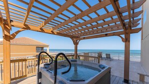 A wooden deck with a hot tub, overlooking the ocean.