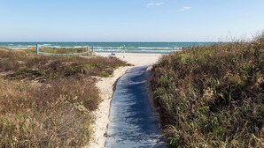 A beach path leading to the ocean, surrounded by vegetation.