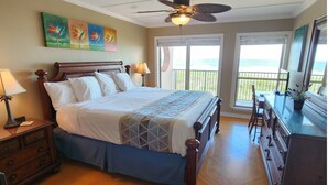 A bedroom with a large bed, a ceiling fan, and a balcony with a view.