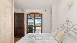 Un dormitorio con cama, una puerta de madera y vistas a una piscina y montañas.