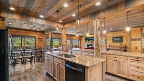Une cuisine spacieuse dotée de meubles en bois, de plans de travail en granit et d’un îlot central avec un évier.