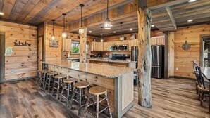 Une cuisine de style rustique, aménagée comme un chalet, avec des murs en bois, un îlot central doté de tabourets et des appareils électroménagers modernes.