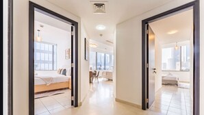 A modern hotel corridor with a bed, a desk, and a view of the city.