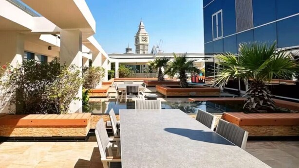 An outdoor seating area with a pool, benches, and a view of a clock tower.