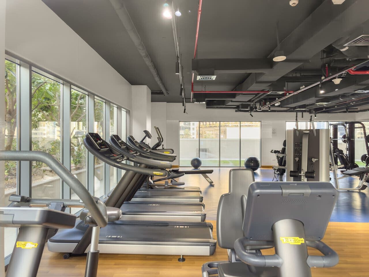 Un gimnasio con cintas de correr, bicicletas estáticas y máquinas de pesas.
