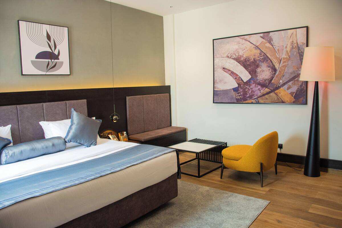 Une chambre d’hôtel moderne avec un grand lit, un canapé, une petite table et une lampe.