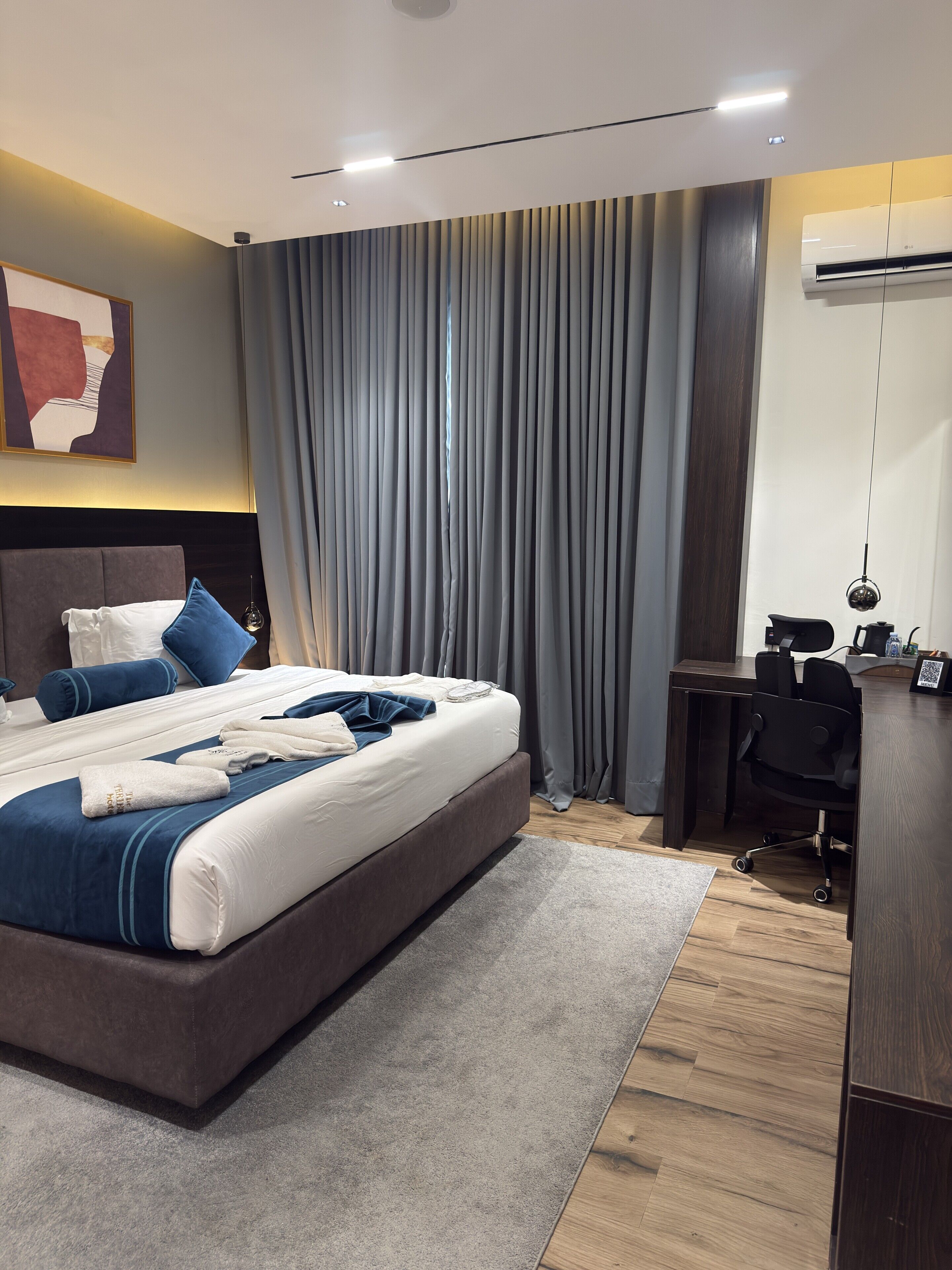 A modern hotel room with a large bed, a desk, and a chair.