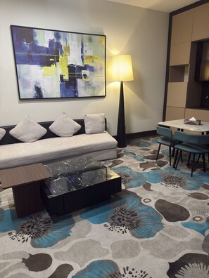 A hotel room with a sofa, a table, a lamp, and a large abstract painting on the wall. - THE THRIBEKA INTERNATIONAL HOTEL (Asaba)