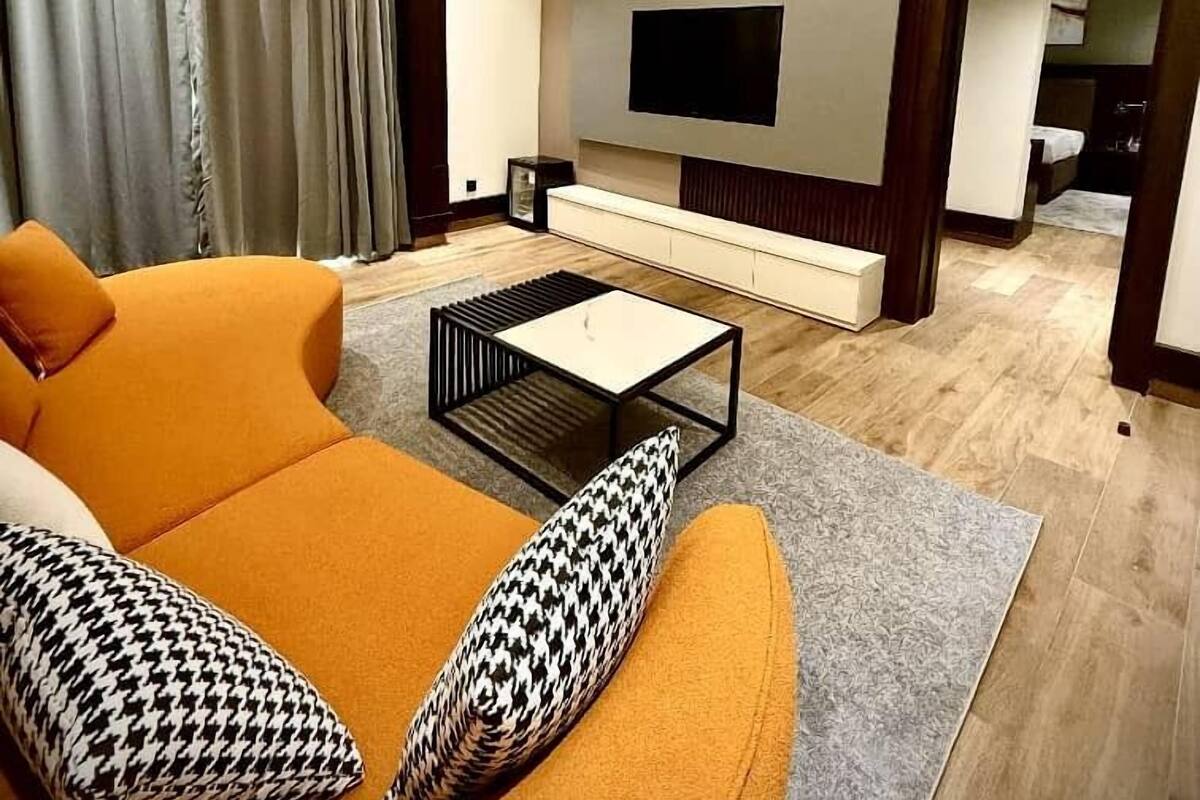 Un salon moderne avec un canapé, une table basse et un téléviseur à écran plat fixé au mur.