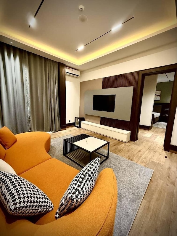 Una sala de estar moderna con un sofá, una mesa de centro y un televisor de pantalla plana montado en la pared.