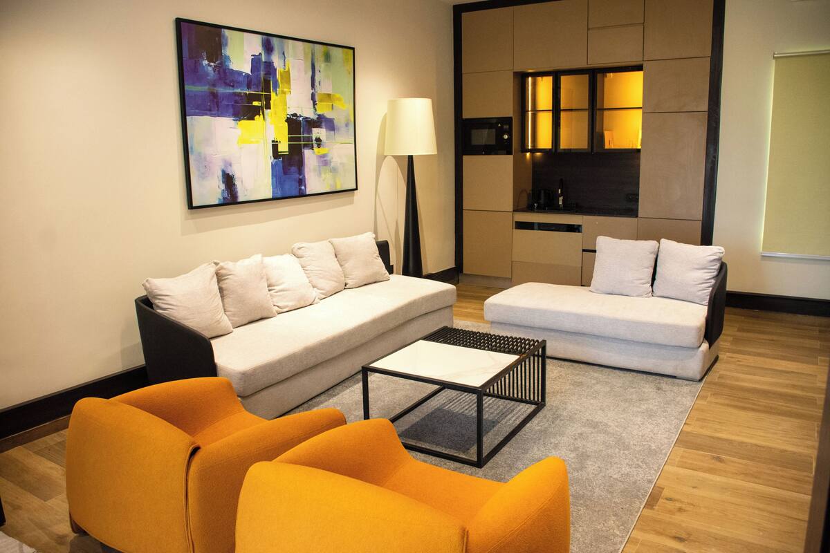 Un salon moderne avec un canapé, deux fauteuils, une table basse et un tableau accroché au mur.