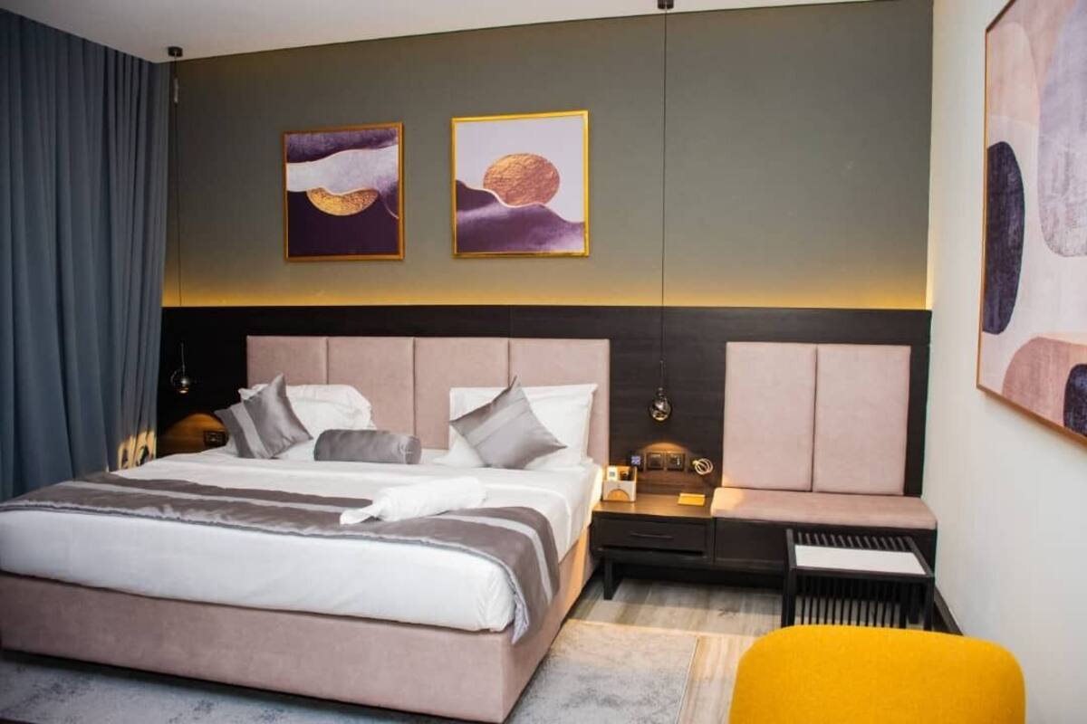 Une chambre d’hôtel moderne avec un grand lit, des tables de chevet et des œuvres d’art accrochées aux murs.
