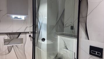 A modern bathroom with a glass shower enclosure, a toilet, and marble-patterned walls.
