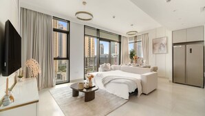 A modern hotel room with a large bed, a dining area, a kitchen, and a TV. - Stylish 2BR — Creek Harbour Views Near Yacht Club & Dining Spots (Dubai Creek Harbour)