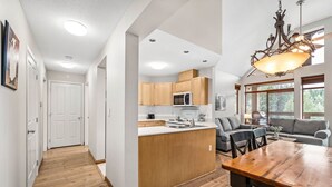 A modern kitchen with wooden cabinets, a central island, and a dining area with a wooden table and chairs.