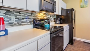 A kitchen with white cabinets, a black microwave, a stainless steel stove, and a black refrigerator. - Cozy Pet-Friendly Condo w/ Pool (Osage Beach)