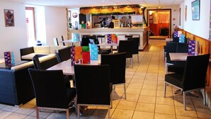 Un ristorante con zona bar, diversi tavoli e sedie, e pavimento piastrellato.