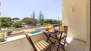 A balcony with a table set for breakfast, a small pool, and a view of the surrounding area. - Apartment pool sea view in Albufeira (Praia da Rocha)