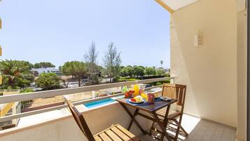 A balcony with a table set for breakfast, a small pool, and a view of the surrounding area.