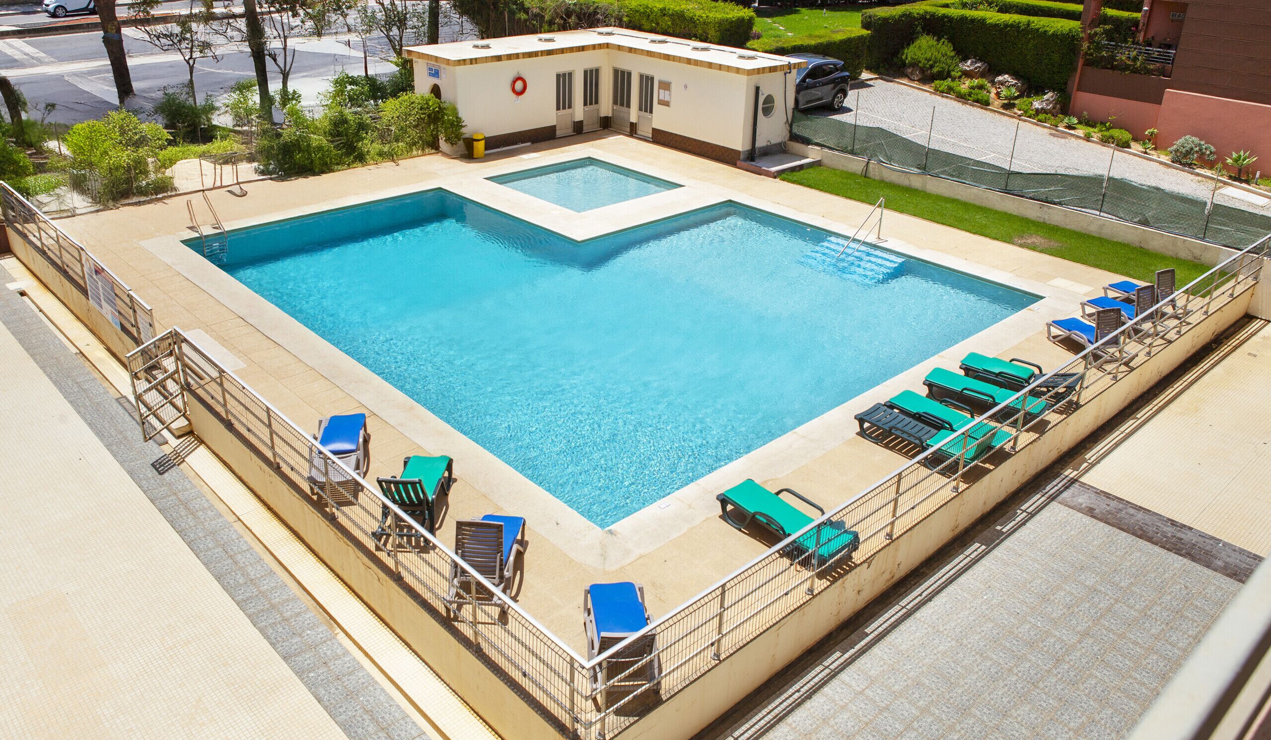 A large rectangular swimming pool with multiple lounge chairs and a lifeguard station.