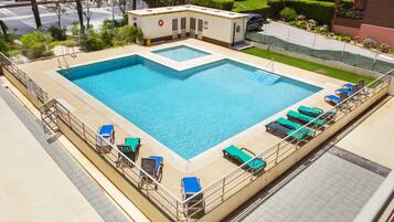 A large rectangular swimming pool with multiple lounge chairs and a lifeguard station.