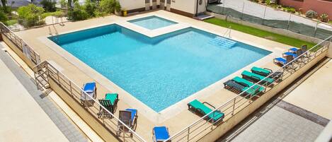 A large rectangular swimming pool with multiple lounge chairs and a lifeguard station.