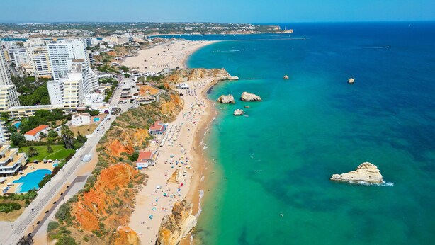 A coastal hotel with a beach, clear blue sea, and rocky cliffs. - Apartment pool sea view in Albufeira (Praia da Rocha)