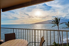 A balcony with a view of the ocean and a mountain in the distance.