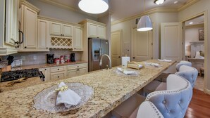 Una cocina amplia con encimeras de granito, armarios blancos y una isla central con asientos.