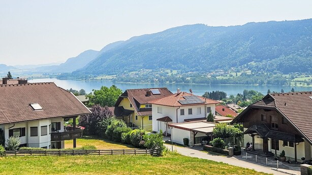 A residential area with houses, a lake, and mountains in the background.