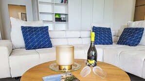 A living room with a round wooden coffee table, a bottle of champagne, two glasses, and a magazine. - Nice apartment for 4 guests with WIFI, TV, patio, pets allowed and panoramic view (Tenero)
