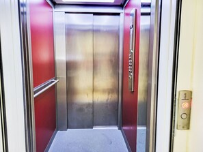 An elevator with metallic doors and a red interior.