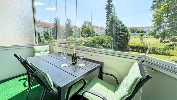 A balcony with a table, two chairs, and a bottle of champagne. - Nice apartment for 4 guests with WIFI, TV and balcony (Dresden)