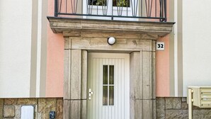A building entrance with a white door, stone pillars, and a balcony with metal railings. - Nice apartment for 4 guests with WIFI, TV and balcony (Dresden)