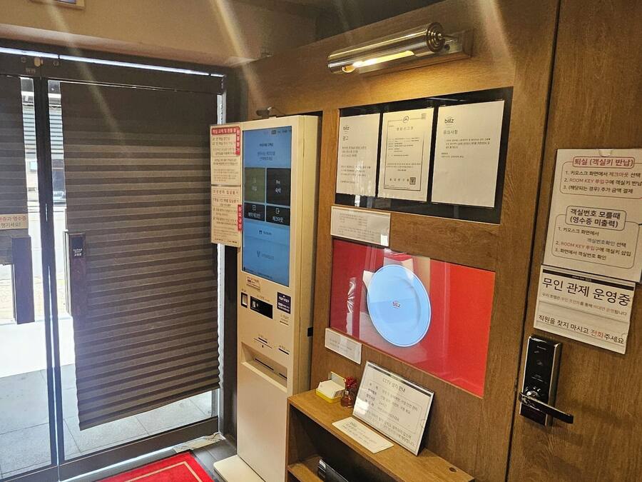Quarto de hotel com porta deslizante, quadro de informações fixado na parede e puxador.