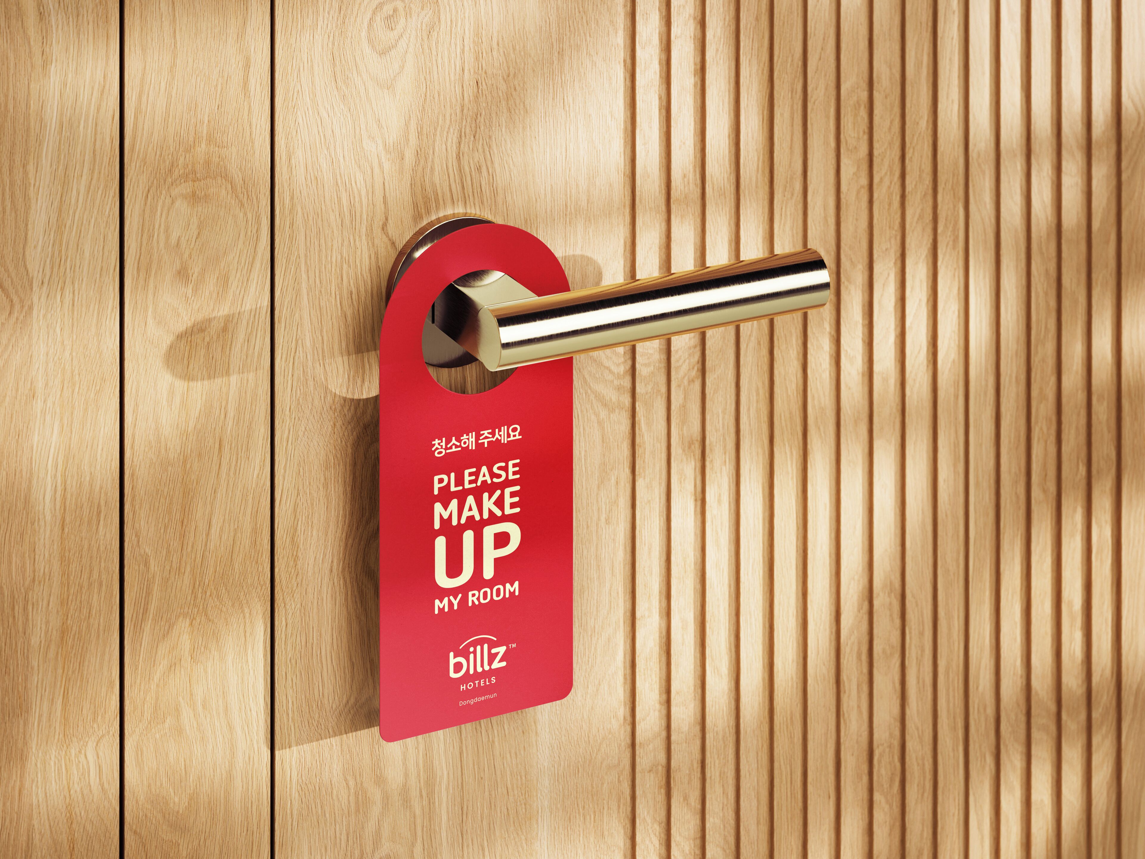 Eine Hotelzimmertür mit einem roten Schild, auf dem 'BITTE ZIMMER REINIGEN' steht, und dem Hotelnamen 'billz hotels'.