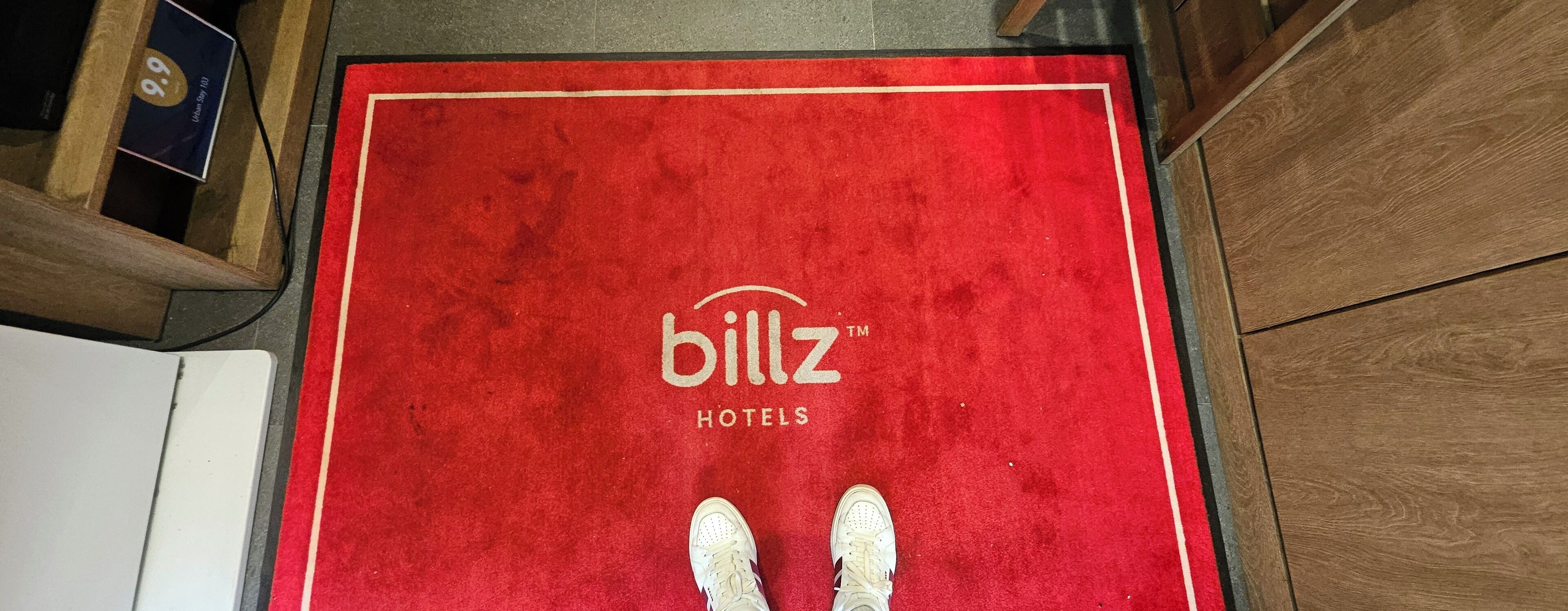 A red carpet with the 'billz Hotels' logo and a wooden floor.