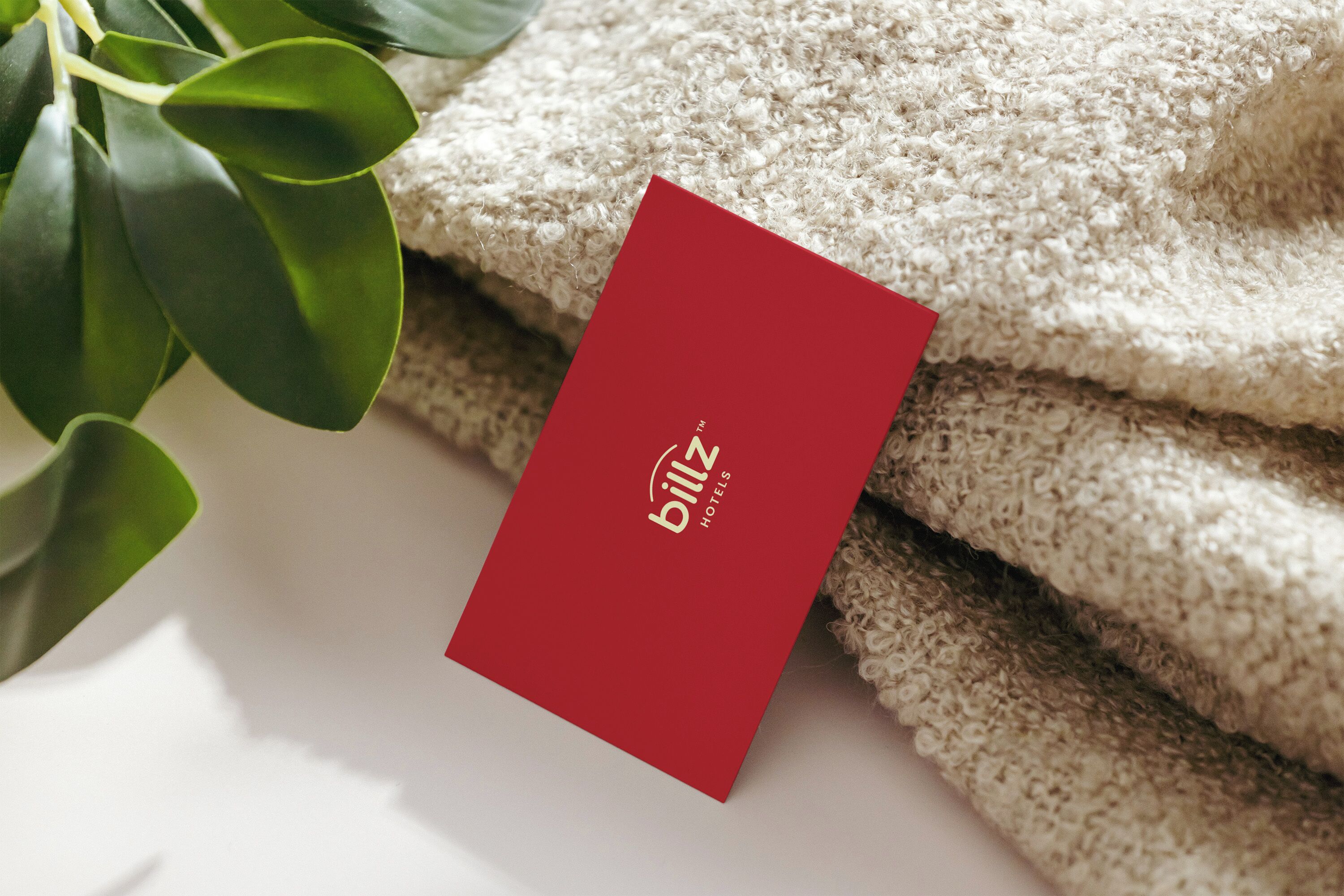A red card with the text "billz hotels" placed on a textured beige surface, possibly a towel or fabric.