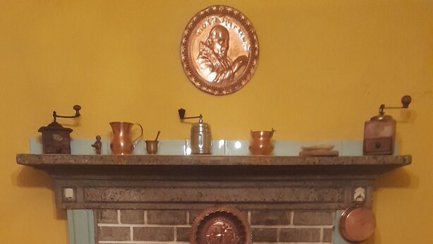 Una habitación acogedora con chimenea, una mesa con una botella, vasos y manzanas.