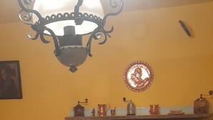 Un salón acogedor con chimenea, una mesa dispuesta con velas, manzanas y vasos, y un tapiz decorativo.