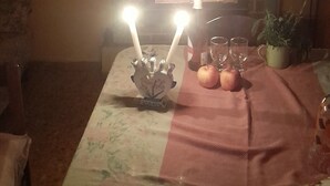 Una sala de estar con chimenea, televisor, una mesa con mantel, velas, manzanas y un control remoto.
