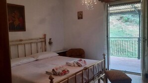 Un dormitorio con cama, candelabro, un cuadro y vistas a un balcón.