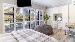 Ein Schlafzimmer mit großem Fenster, einem Bett, einem Schreibtisch und einem Stuhl.