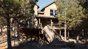 A two-story house with a covered porch and a staircase leading to a deck. - Bluebird Day - Big River, Luxurious 4BR home in Bend, perfect for families or groups of up to 8. (Bend)