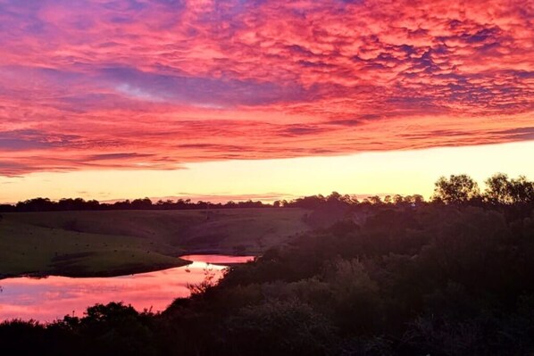 A sunset over a valley with a river reflecting the sky. - Lake Entrance Home with Stunning View (Lake entrance)