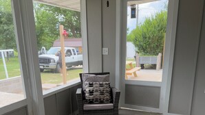 A room with a wicker chair, a glass-top table, and a patterned rug. - Farmhouse Fantasy (Nauvoo)