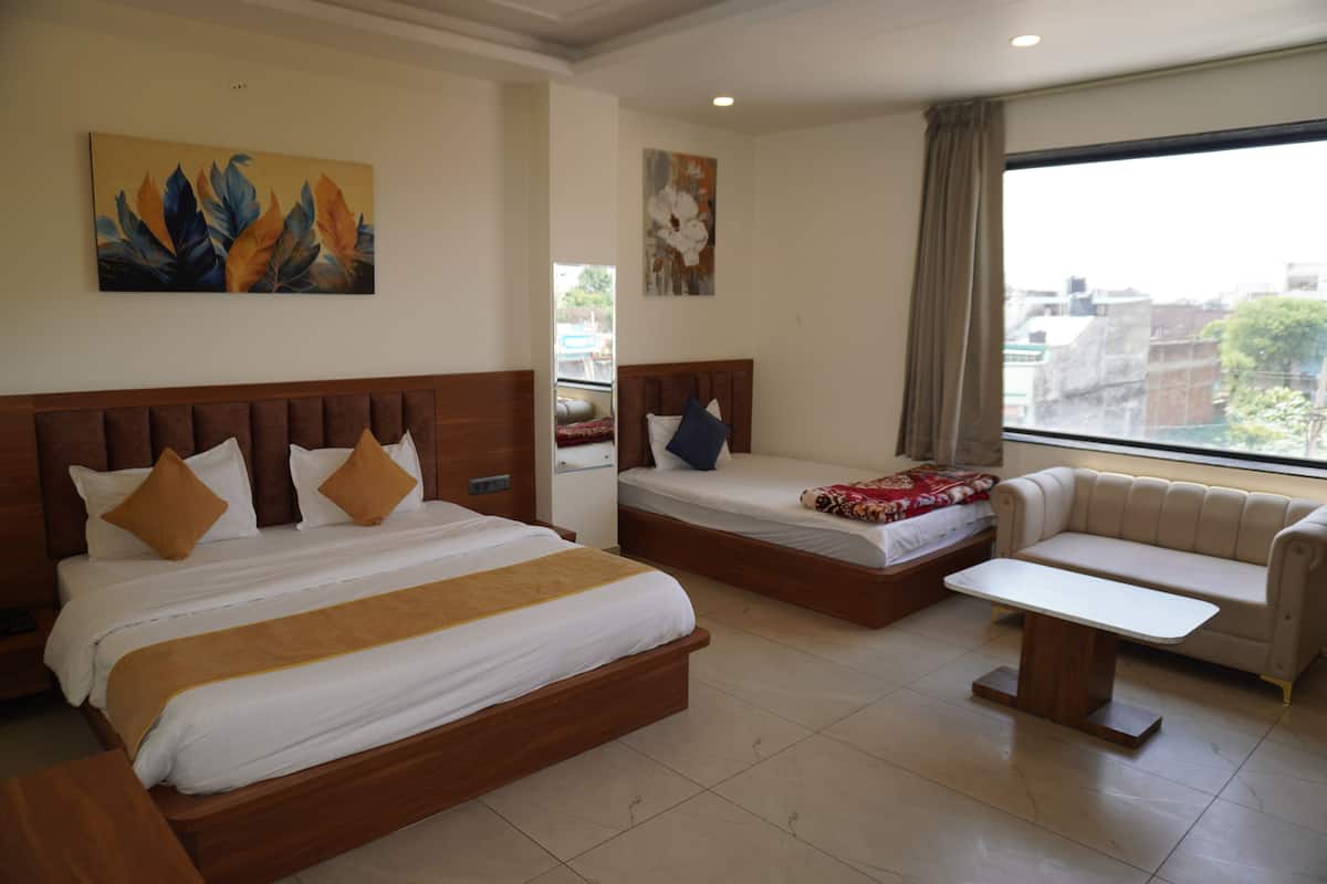 Habitación de hotel con dos camas, un sofá, una mesita y obras de arte en las paredes.
