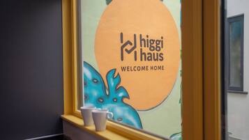 A window with a 'higgi haus' sign and a view of a building's interior.